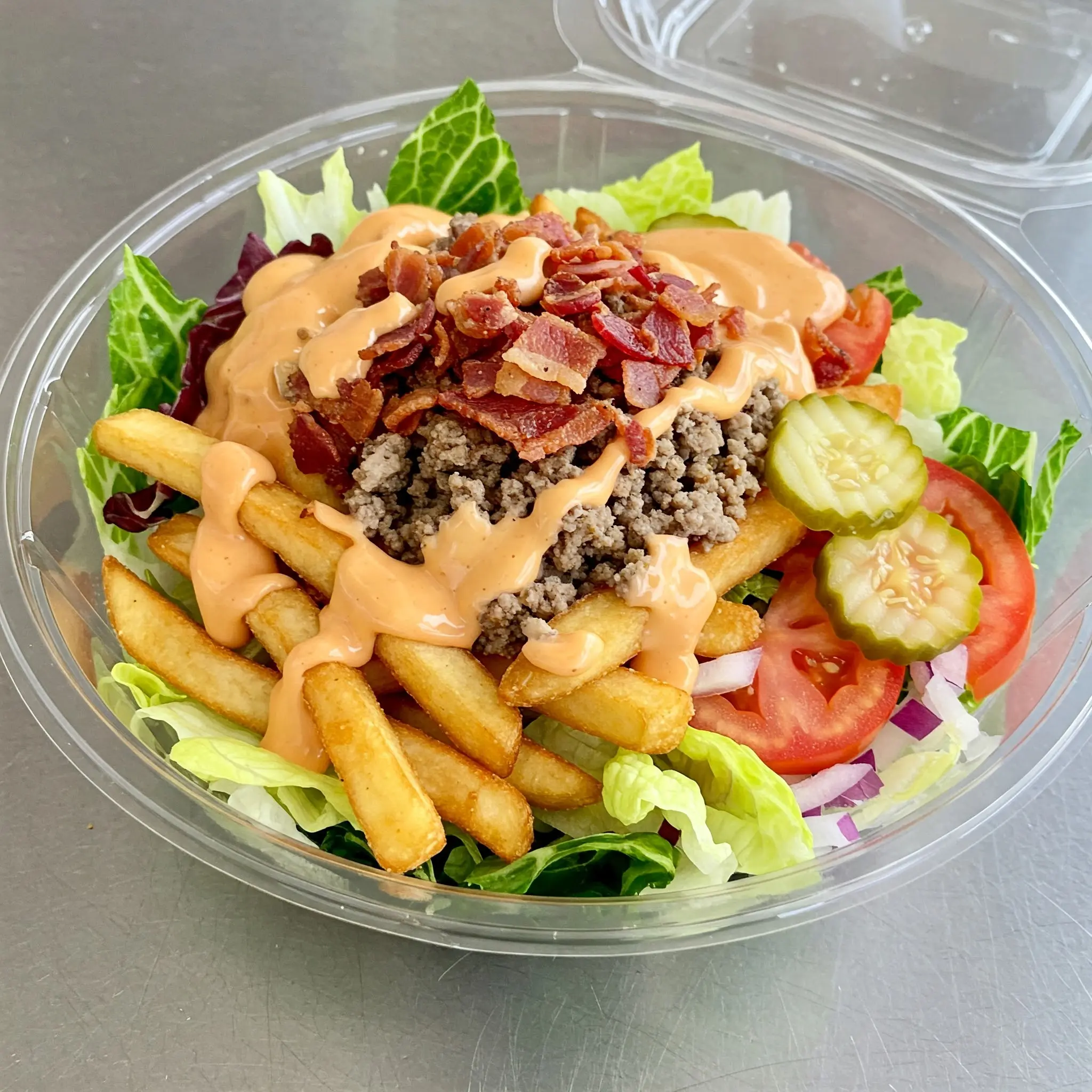 Salad with fries, bacon, and dressing.