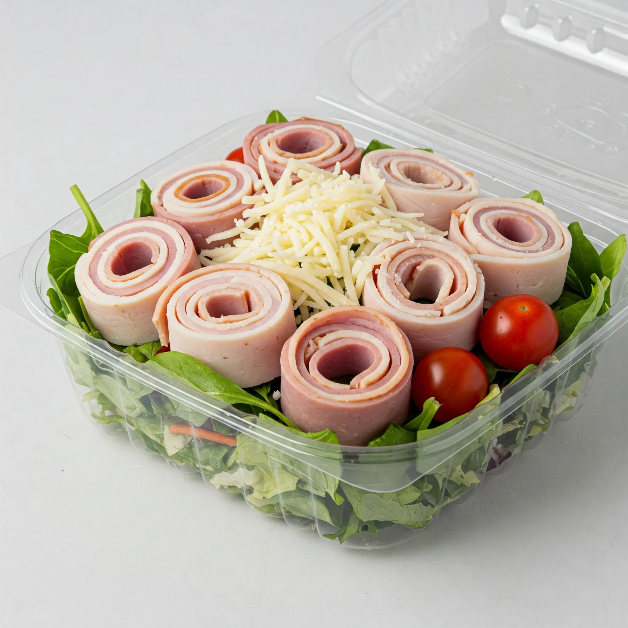 Salad with ham rolls and cheese topping.
