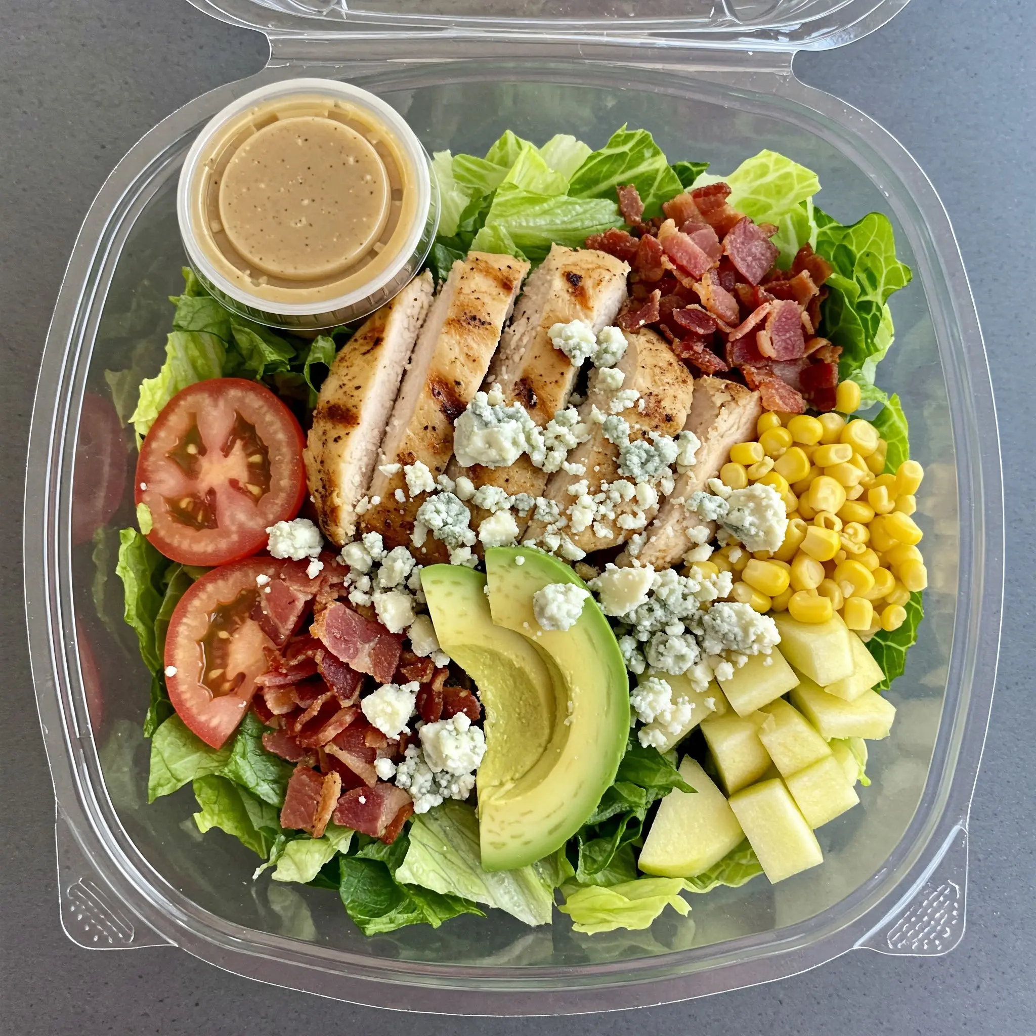 Salad with chicken, avocado, bacon, and dressing.