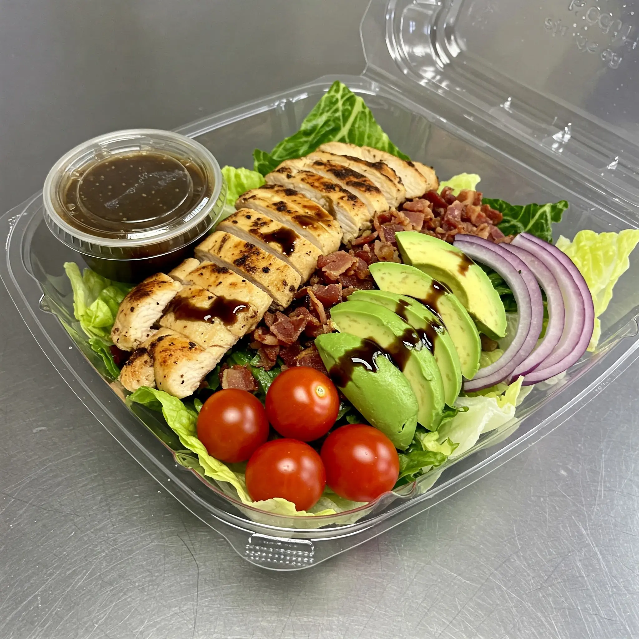 Chicken salad with avocado and dressing container.