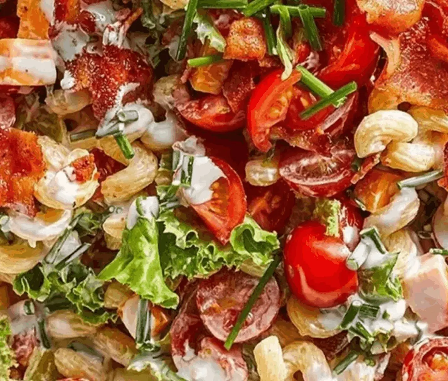 Salad with tomatoes, lettuce, bacon, and cashews.
