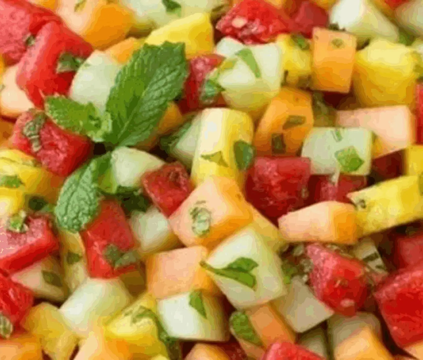 Colorful fruit salad with fresh mint leaves.