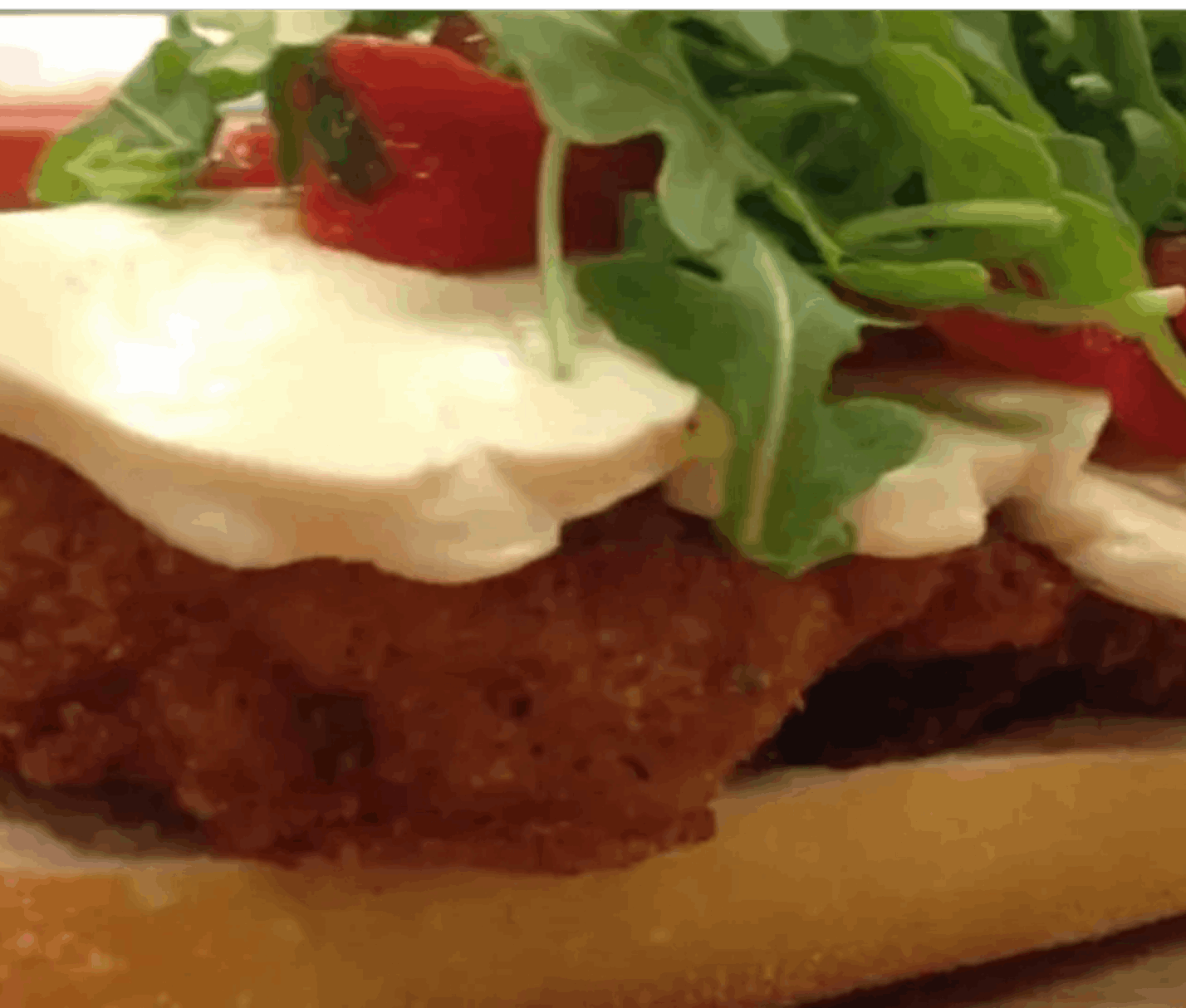 Chicken sandwich with cheese and arugula.